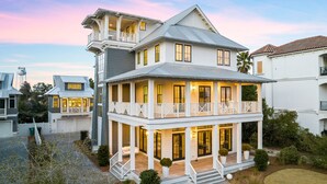 A two-story house with a balcony, a covered porch, and a small garden. - Spacious Porch with Pool and Firepit (Panama City Beach)