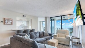 A modern living room with a grey sofa, a beige armchair, and a flat-screen TV.