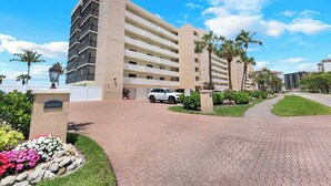 A multi-story hotel with a central courtyard, palm trees, and a paved walkway.