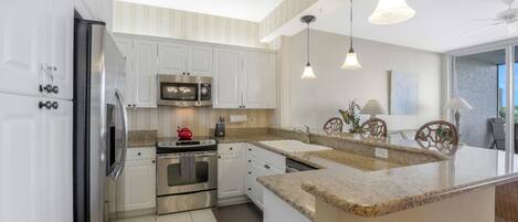 A modern kitchen with white cabinetry, stainless steel appliances, and a granite countertop.