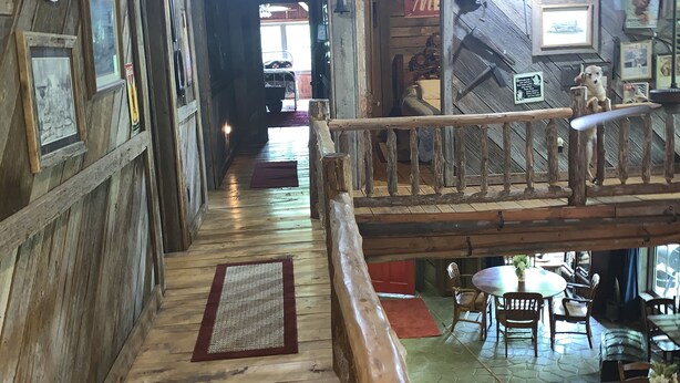 A wooden interior with a central walkway, rustic decor, and a dining area with tables and chairs. - Enjoy the River Breeze (Tompkinsville)