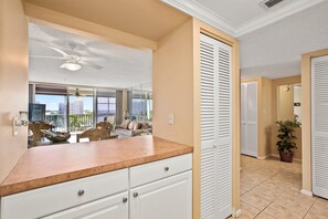 Quarto de hotel com varanda, ventoinha no teto, espaço de refeições e vista para a cidade.