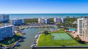 A marina with boats, a tennis court, and high-rise buildings. - Vanderbilt Towers - Walk to the Beach! (Naples)