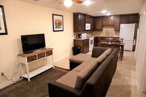 Ein Wohnzimmer mit Fernseher, Sofa und Essbereich mit Tisch und Stühlen.