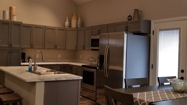 Una cocina moderna con una isla central, electrodomésticos de acero inoxidable y una zona de comedor con mesa y sillas.