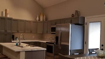 Une cuisine moderne dotée d’un îlot central, d’appareils électroménagers en acier inoxydable et d’un coin repas avec une table et des chaises.