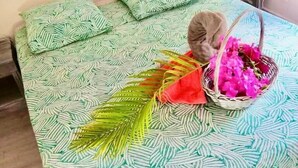 A bed with a patterned bedspread, a basket of flowers, and a green lamp on a bedside table. - LE FLAMBOYANT, triplex sea view, 3 bedrooms, residence with swimming pool (le Gosier)