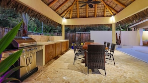 An outdoor kitchen area with a grill, dining table, and chairs. - Macaws and Sloths and Monkeys, Oh My! Villa Capuchin in Manuel Antonio (Manuel Antonio)