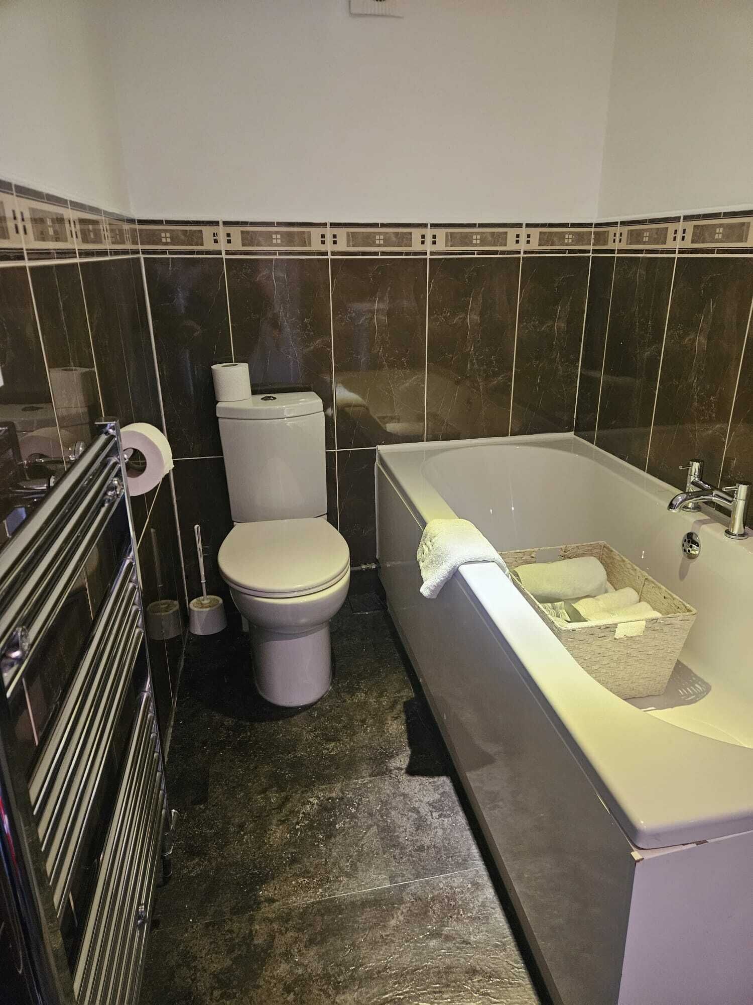 A bathroom with a toilet, a bidet, a bathtub, and a towel rack.