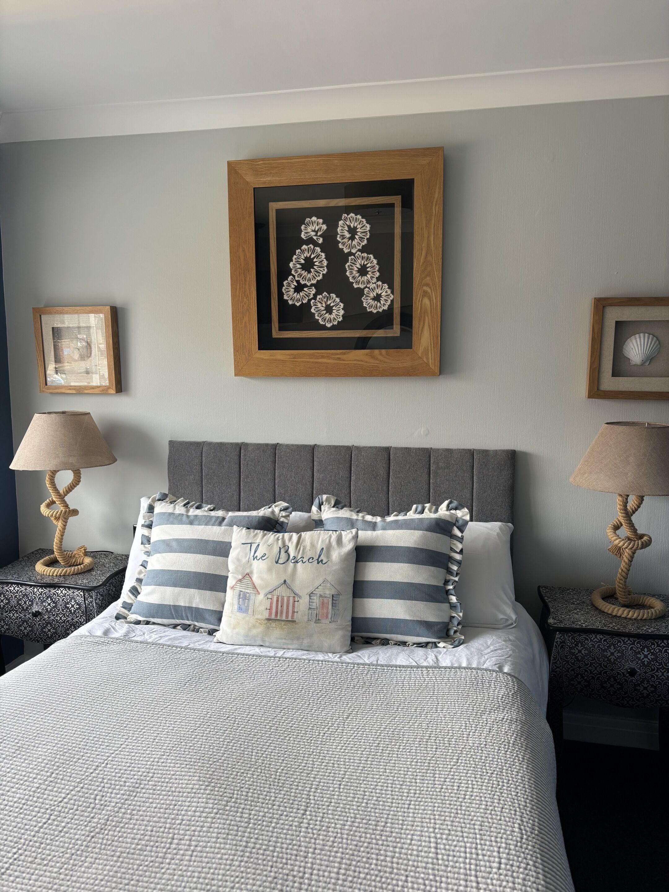 A neatly arranged bedroom with a bed, two nightstands, and a framed artwork above the bed.
