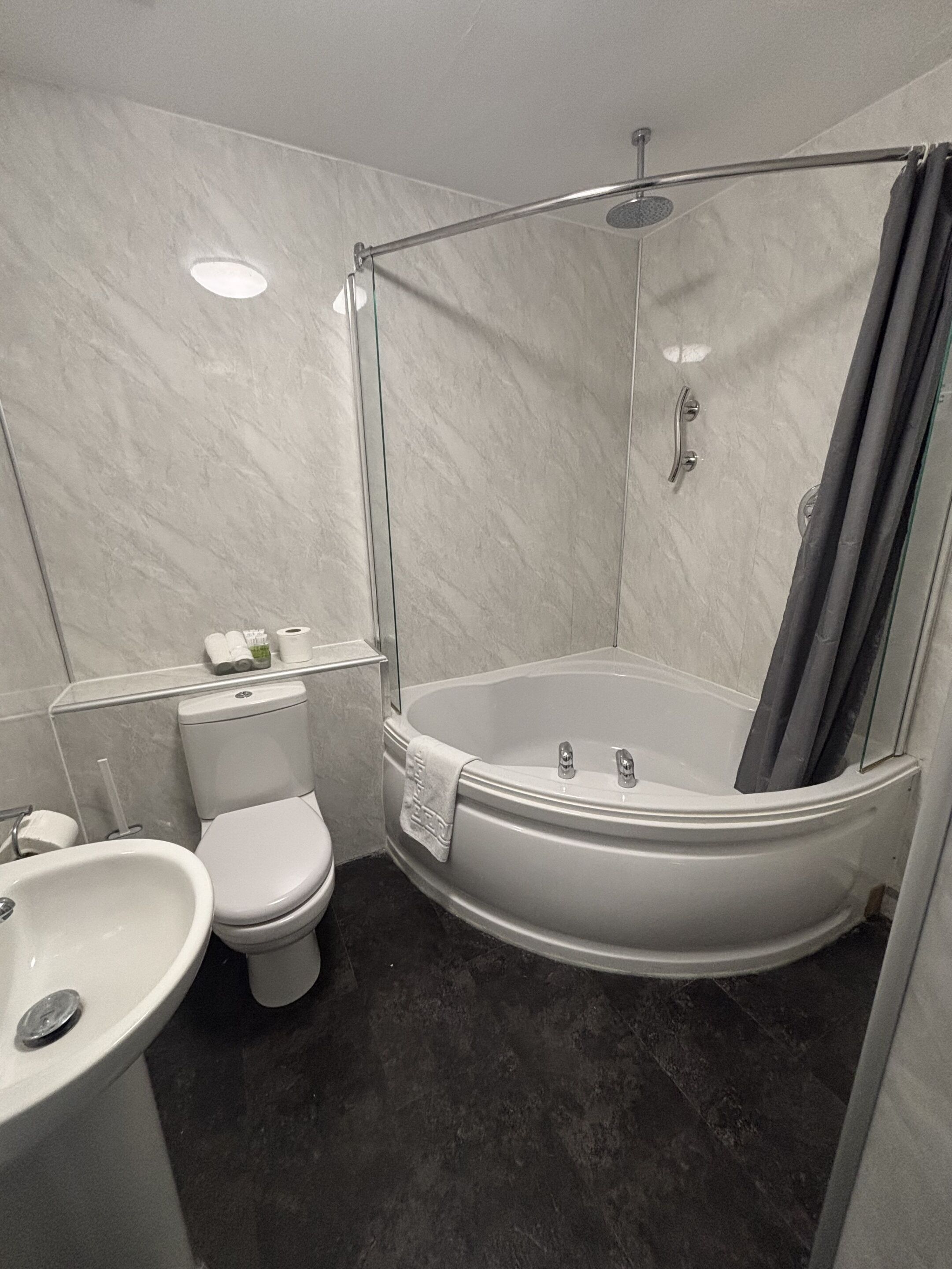 A bathroom with a toilet, sink, and a walk-in shower with a glass door.