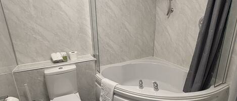 Un baño con inodoro, lavamanos y cabina de ducha con puerta de cristal.