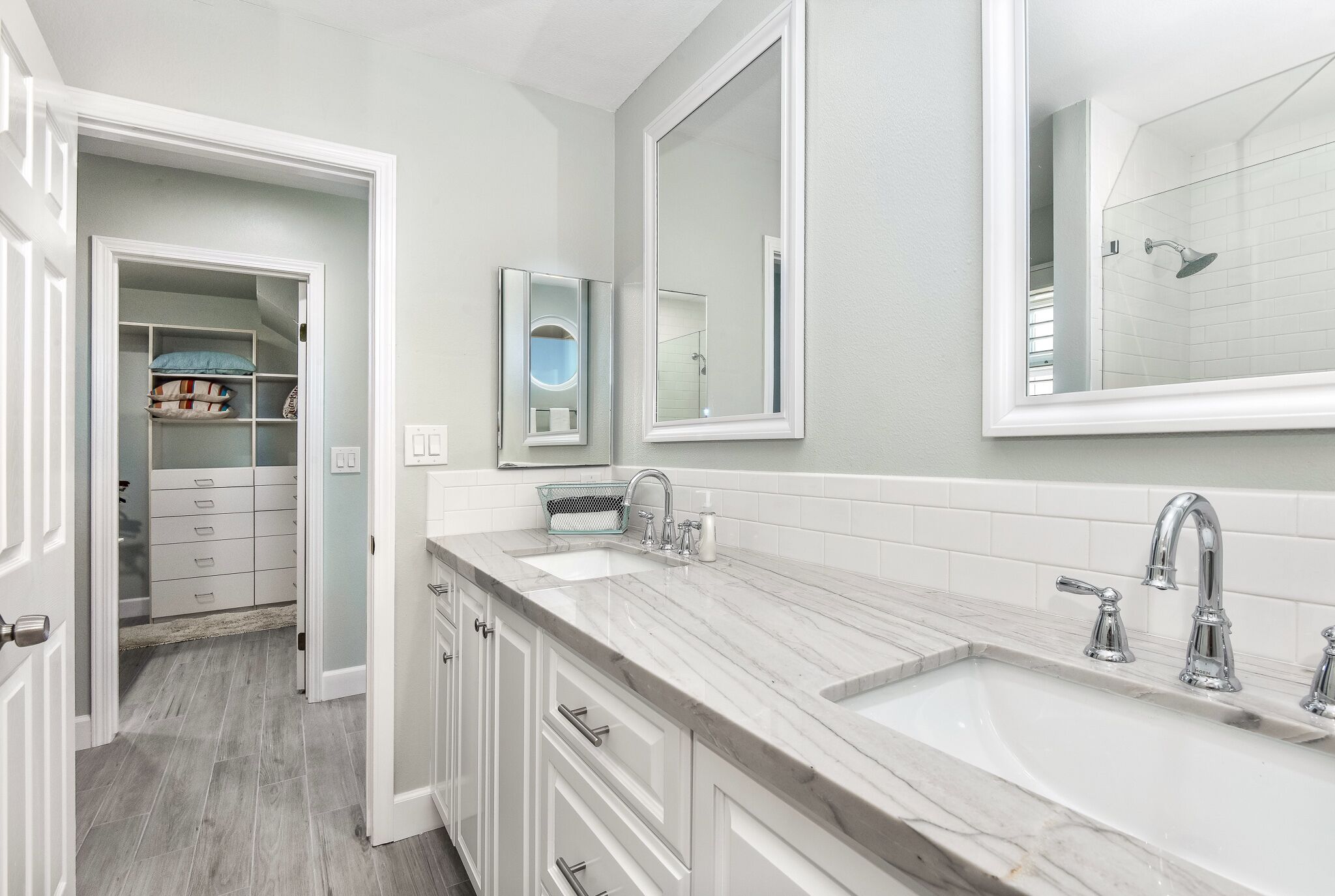 A modern bathroom with a double sink, large mirror, and a walk-in shower.