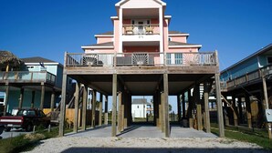 A two-story building with a balcony on the upper floor, supported by wooden stilts. - Walk to Crystal Beach: Chic Family Retreat w/ Deck (Bolivar Peninsula)