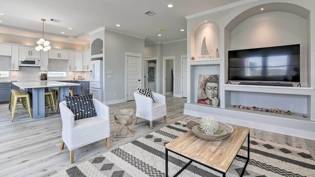 A modern kitchen with white cabinets, a central island, and gold bar stools. - Walk to Crystal Beach: Chic Family Retreat w/ Deck (Bolivar Peninsula)