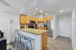 Cocina moderna con encimeras de granito, electrodomésticos de acero inoxidable y armarios de madera.