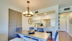 A dining area with a large table, blue chairs, and a chandelier. - Nautical Edgewater Resort Condo - Walk to Beaches! (Panama City Beach)