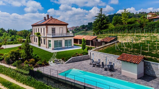 A large house with a swimming pool, a garden, and a view of the surrounding landscape.