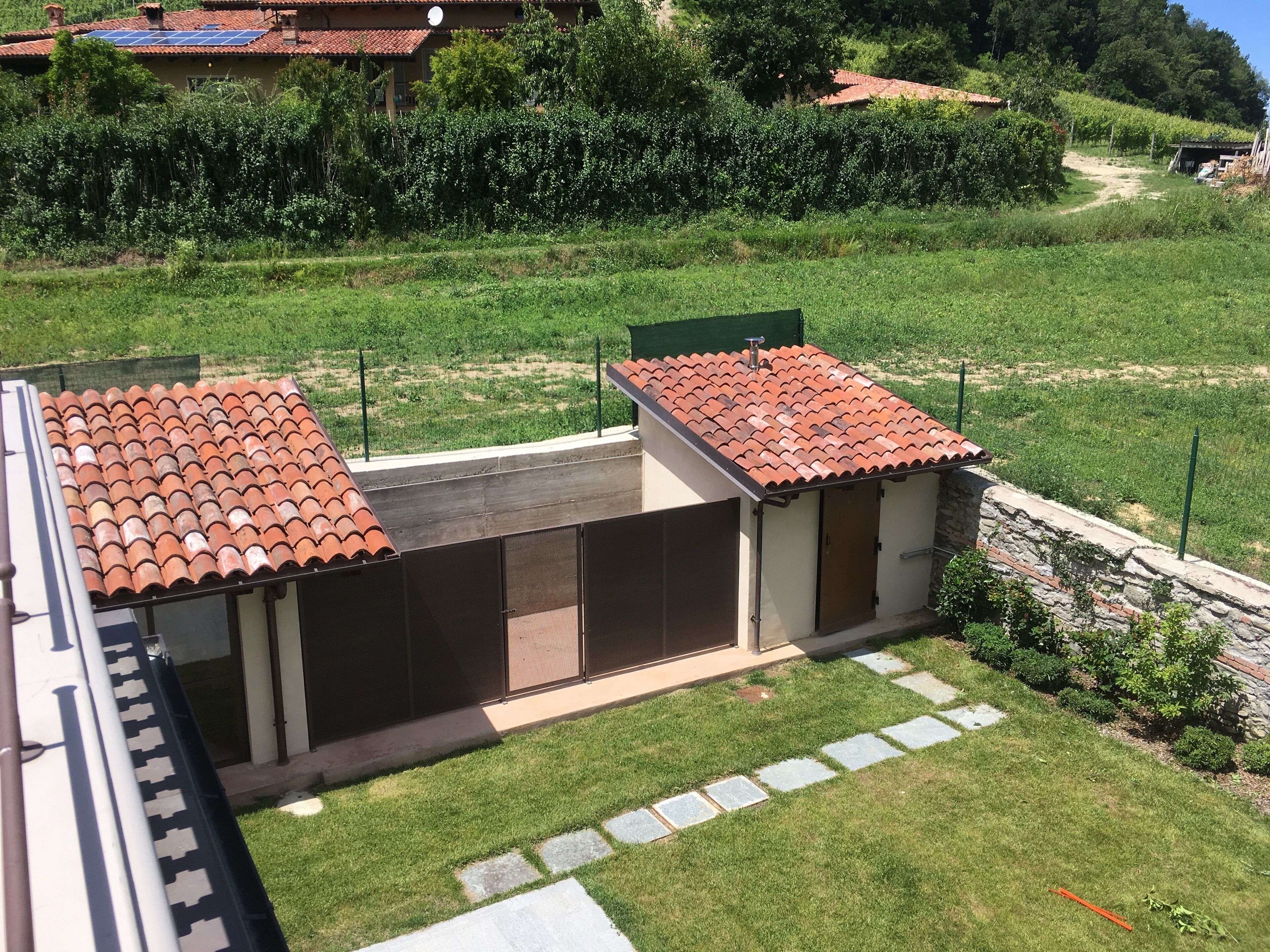 Un petit bâtiment d’un seul étage, doté d’un toit en tuiles, d’une terrasse entourée d’une clôture et d’un mur en pierre.