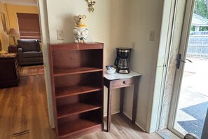 Une pièce avec une bibliothèque en bois, une machine à café et une fenêtre donnant sur une clôture.
