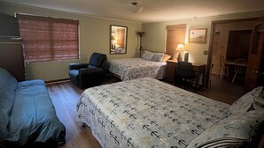 Ein Zimmer mit zwei Betten, einem Schreibtisch, einem Stuhl und einem Fenster mit Jalousien.