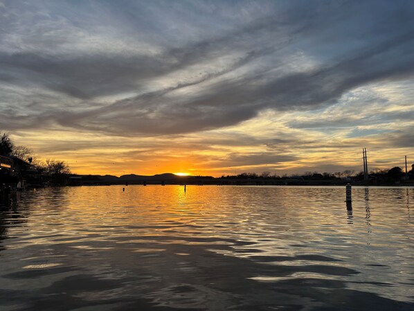 Un atardecer sobre una masa de agua tranquila, con un puente a lo lejos.