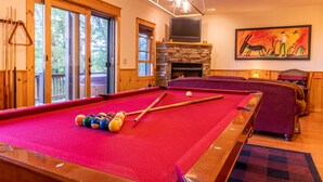 Une table de billard avec des billes, une cheminée et un tableau accroché au mur.