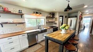 A modern kitchen with a wooden island, stainless steel appliances, and a large window providing natural light.