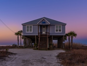 A two-story house with a balcony, a wooden staircase, and palm trees. - Bayfront with Private Pool! Outdoor games, modern style! - The Blue Crab (Dauphin Island)