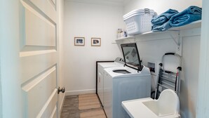 Pesuhuone, jossa on pesukone, kuivausrumpu ja pyykkien taitospöytä.