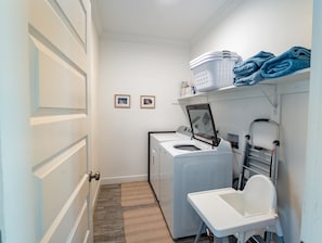 A laundry room with a washing machine, dryer, and a folding table.