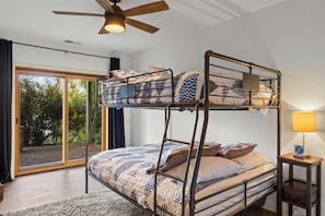Camera con letto a castello, ventilatore a soffitto, lampada e vista sul verde.
