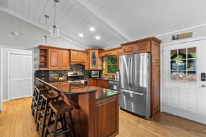 A modern kitchen with wooden cabinets, stainless steel appliances, and a large island with bar stools.
