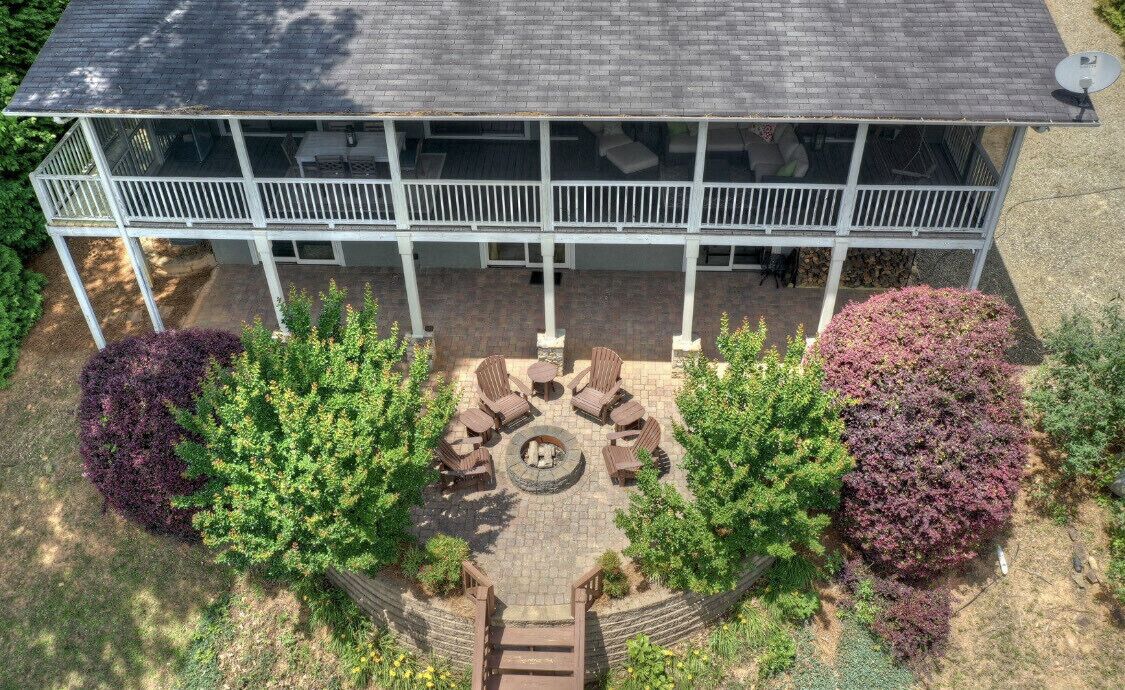 Une maison à deux étages dotée d’un patio couvert comprenant un espace salon extérieur et un foyer.