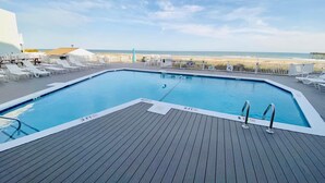A pool with a wooden deck, lounge chairs, and a view of the beach. - Enjoy Sunset Views at Cozy Oceanfront Condo + Pool on Ocean Isle Beach, NC (Ocean Isle Beach)