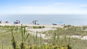 Ein Strand mit Personen, Sonnenschirmen und Liegestühlen.