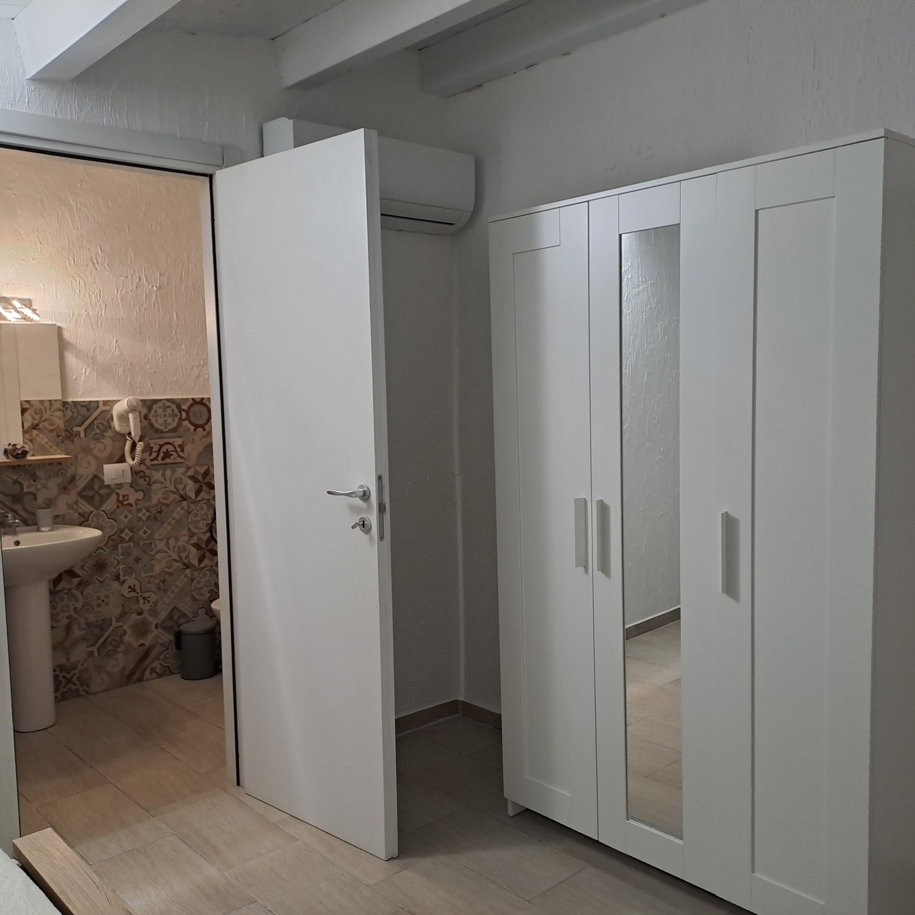Une salle de bain avec un lavabo blanc, des carreaux décorés et une armoire blanche à deux portes.