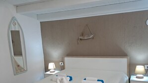 Un lit bien fait, avec des serviettes blanches et bleues, une tête de lit en bois et un petit objet décoratif accroché au mur.