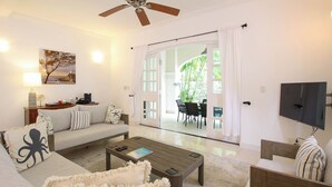A living room with a sofa, coffee table, and TV. There's a dining area with chairs and a table. - Private Pool, 3 mins from Beach - Turtle View 2 (Porters)