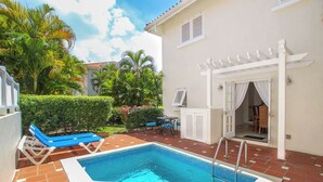 A swimming pool with a white deck, a covered patio area, and a view of a lush garden with palm trees. - Private Pool, 3 mins from Beach - Turtle View 2 (Porters)
