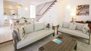 A modern living room with a sofa set, a coffee table, and a dining area with chairs and a table. - Private Pool, 3 mins from Beach - Turtle View 2 (Porters)
