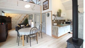 A cozy kitchen with a dining area, a black stove, and a stone wall.