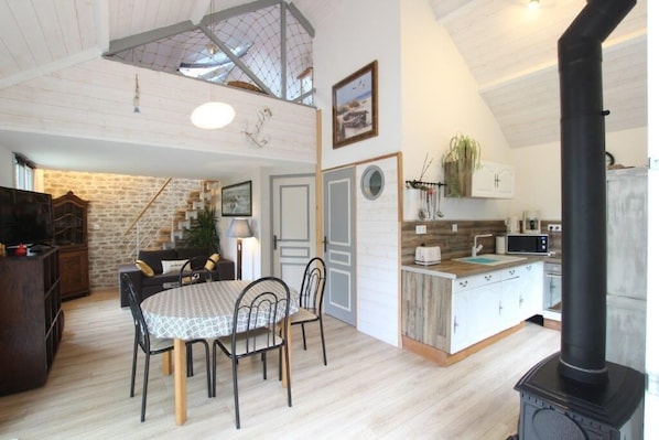 A cozy kitchen with a dining area, a black stove, and a stone wall.