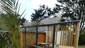 A wooden deck with a picnic table and a small building with a sloped roof.