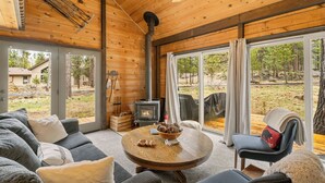 A cozy cabin interior with a fireplace, wooden walls, a round table, and a sofa. - Quintessential Cabin in Sunriver's Best Location  - Cluster Cabin #2 (Sunriver)