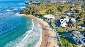 Vista aérea de una zona costera con playa, edificios residenciales y un campo de golf.