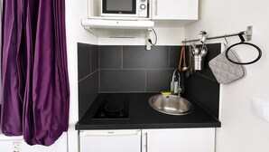 Een moderne keuken met een zwart aanrecht, een roestvrijstalen spoelbak, een magnetron en een waterkoker op de plank.