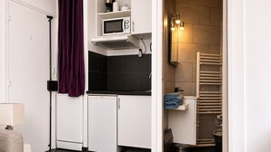 Een compacte keuken met een magnetron, een kleine koelkast en een ingebouwde oven.