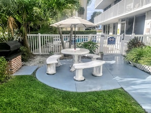 Relax in the serene outdoor patio area, surrounded by lush greenery and a brick barbecue grill.