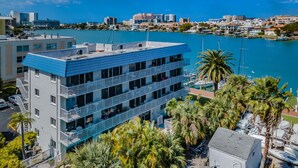 A multi-story hotel with balconies, located near a marina with boats and palm trees.